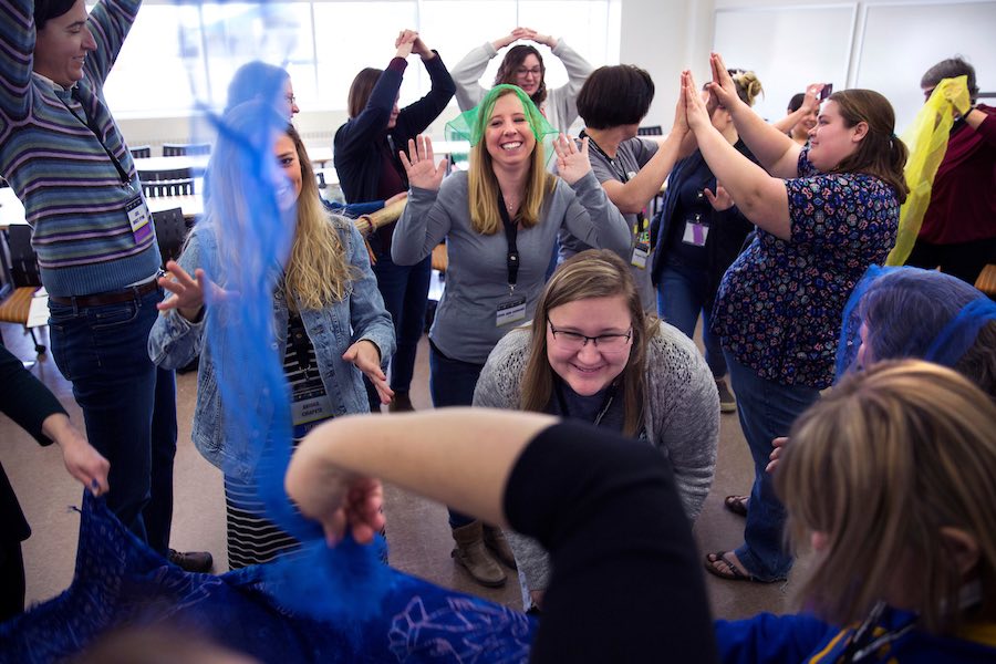 A group of people smile and laugh together as they clap hands with each other.