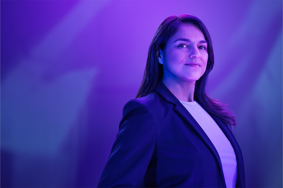 A person wearing a blazer smiles into the distance.