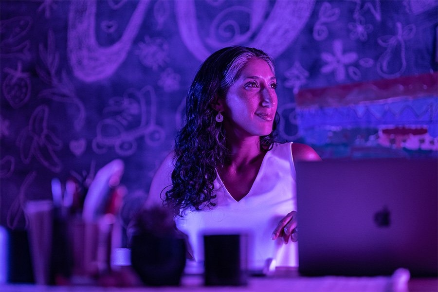A person in a purple light works on a computer.