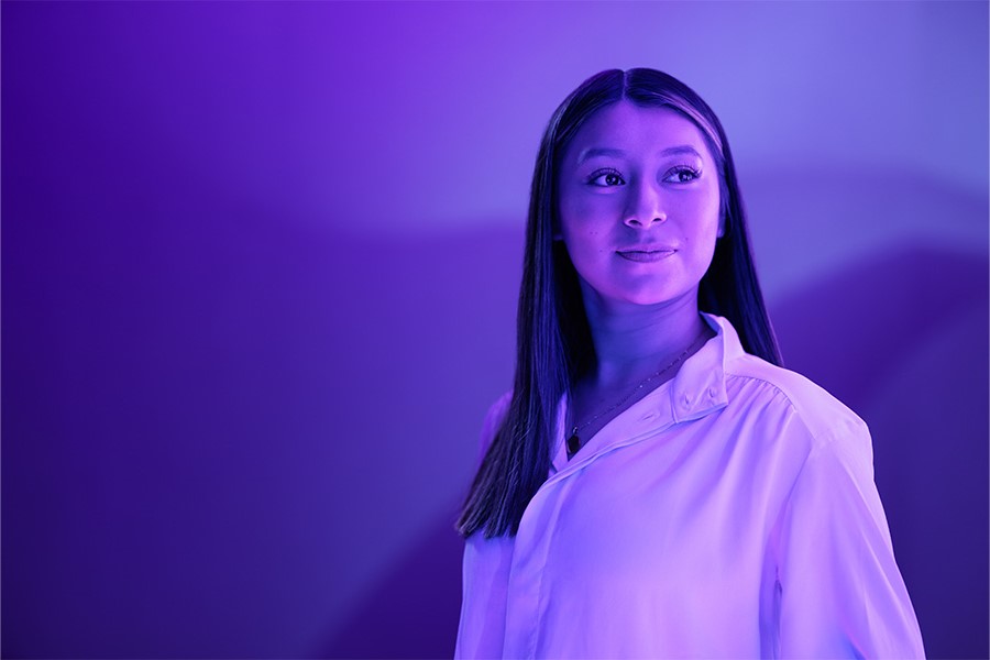 A person in a purple light looks off into the distance.