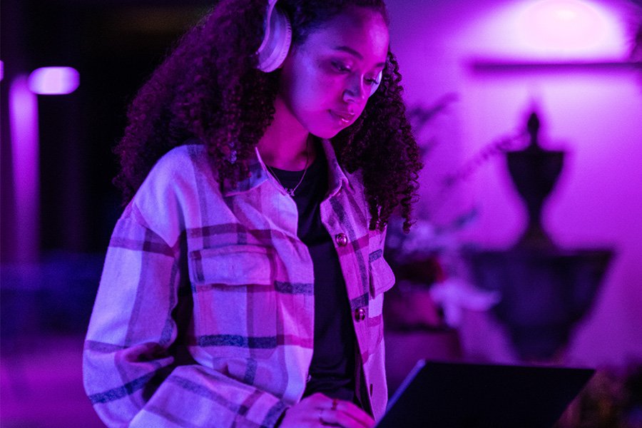 A person wearing headphones stands in purple lighting.