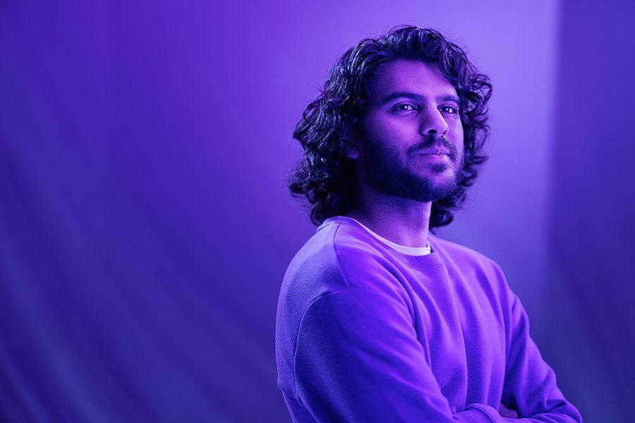 A person in a purple light looks off into the distance.
