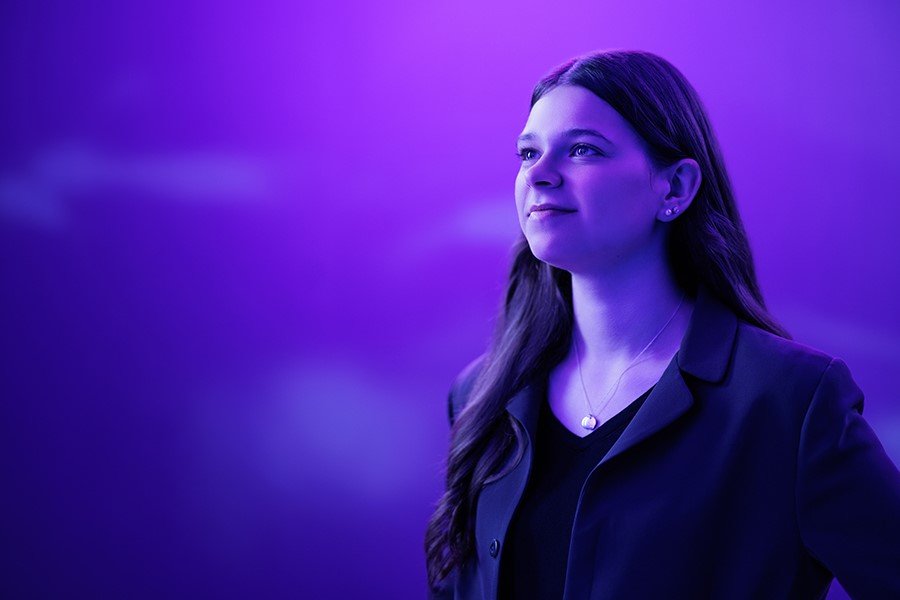 A person in a purple light looks off into the distance.