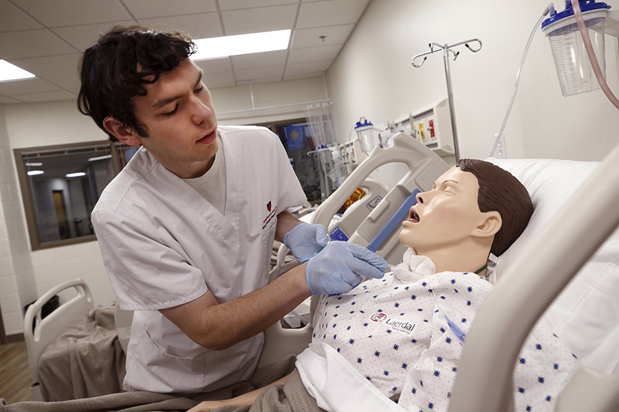 A student uses a stethoscope to listen to another student's chest.