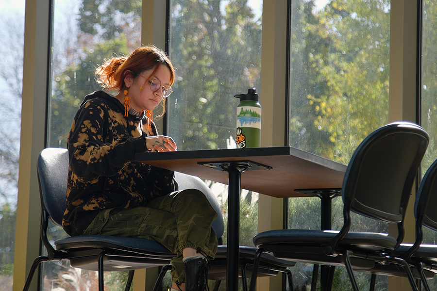 A person studies while sitting at a table with large windows behind them.