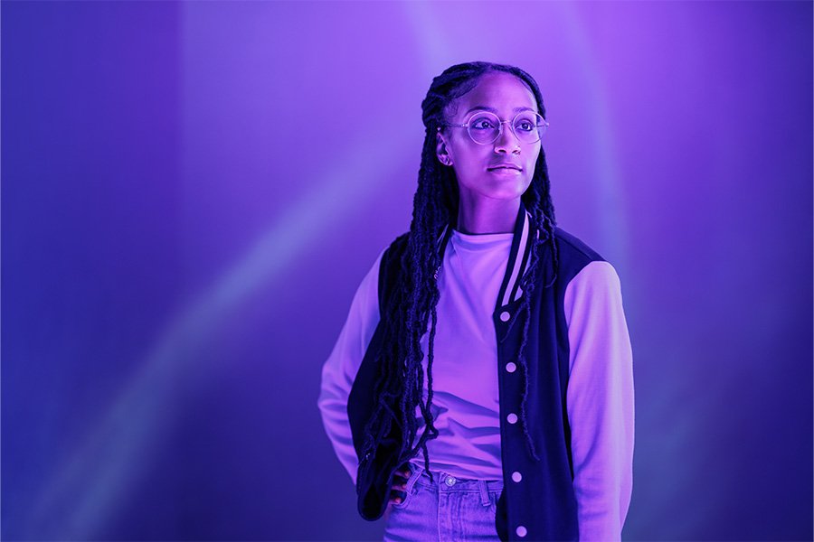 A person stands with their hand on their hip in purple lighting.